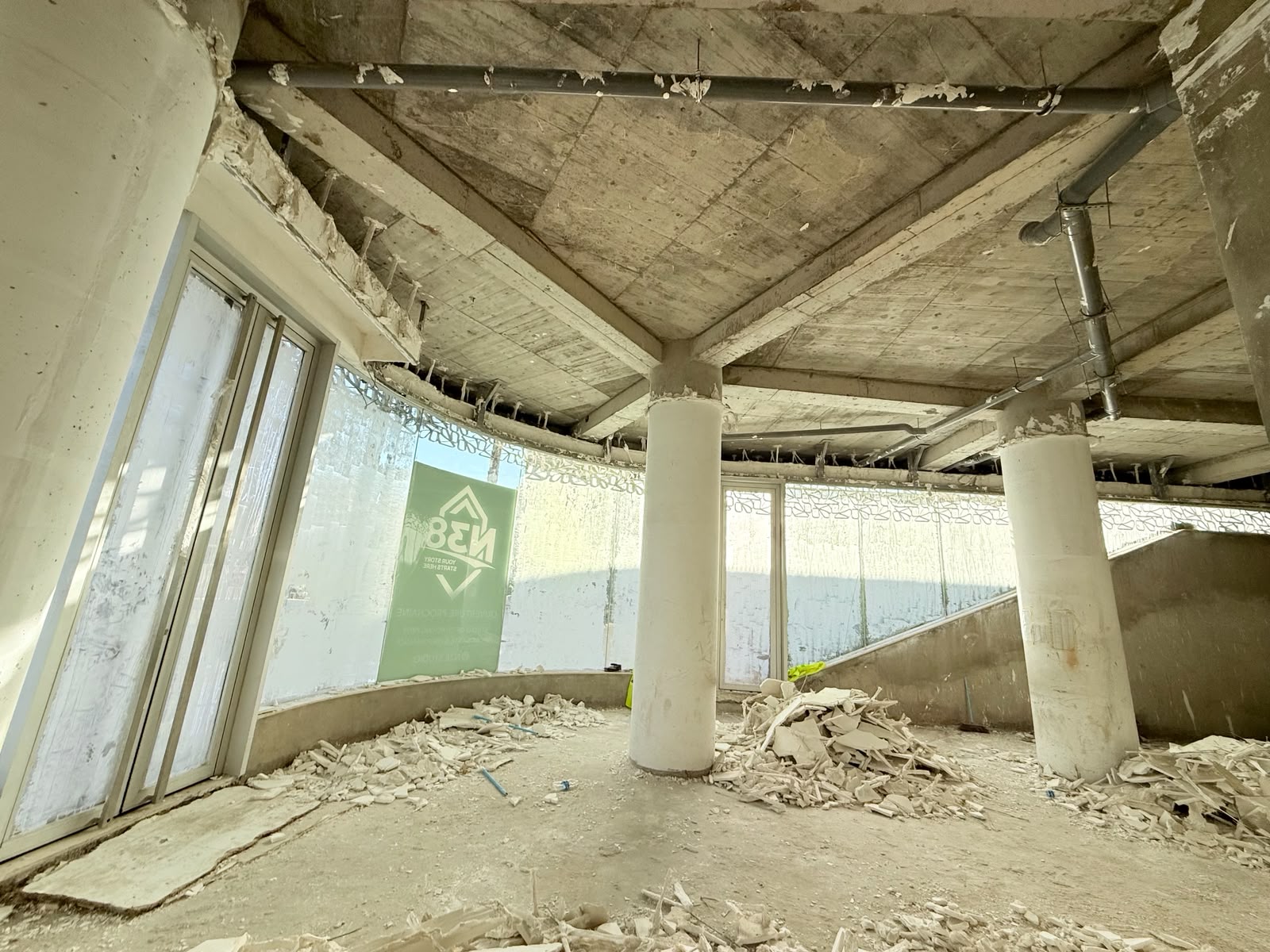 La façade courbe vitrée du studio, colonnes et gravats au sol